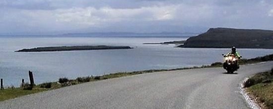 Motorradfahrer auf einsamer Küstenstraße Schottlands
